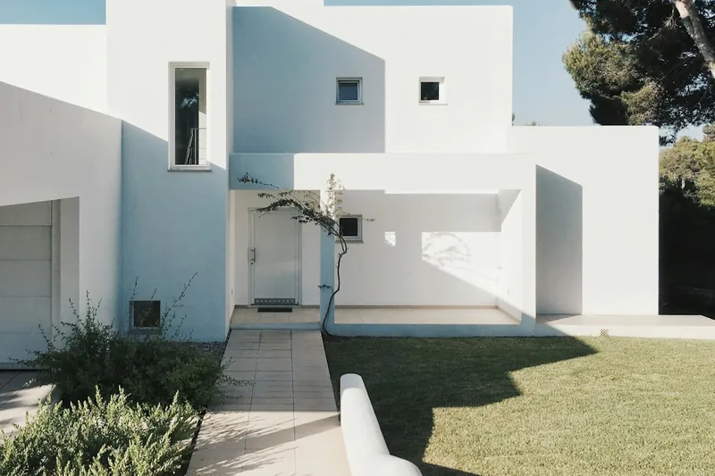 White masonry garden walls enclosing a paved entry path and lawn.