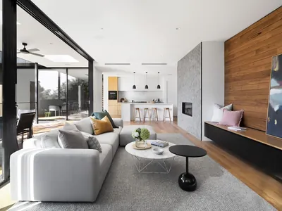 An open-plan living space with a full-height glazed wall folded open to the exterior.