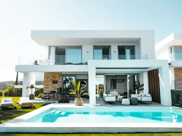 Pale paved terrace running to the edge of a pool with planting beyond.