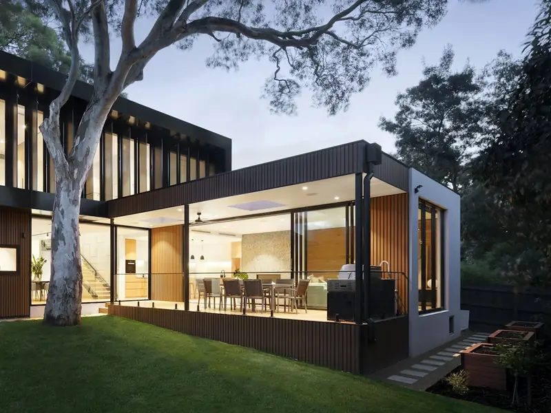Covered terrace with a dining setting lit from the house at dusk.
