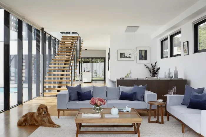 Seating area with a low sofa and staircase beside a glazed wall.