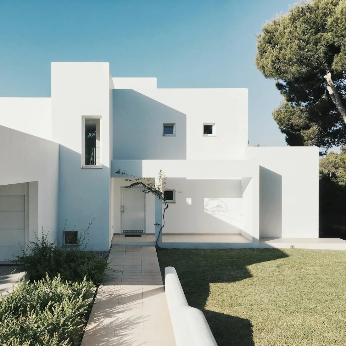 Bright white stucco exterior with stone steps under a clear blue sky.